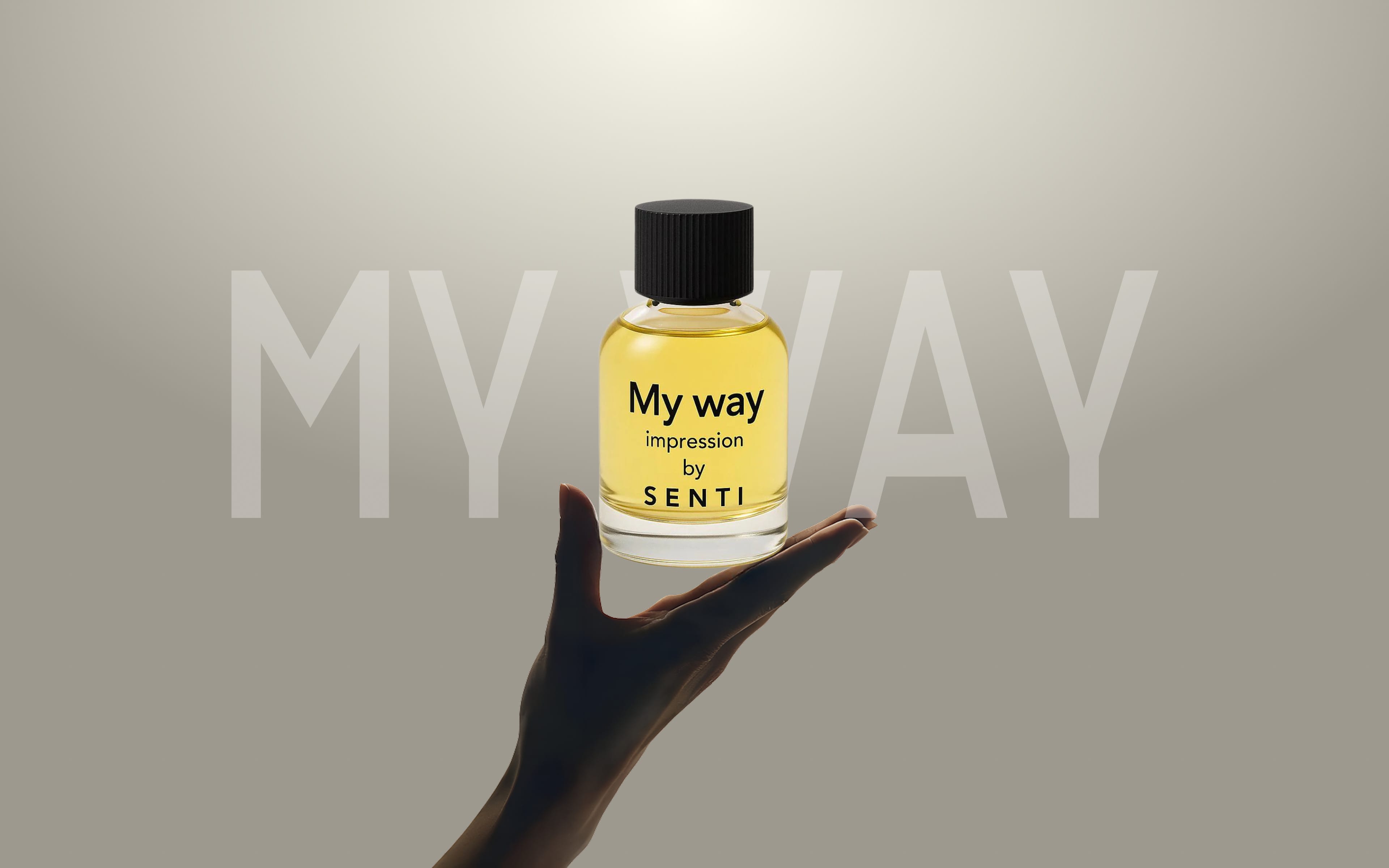 A hand gently presenting a clear Senti 'My Way' Impression perfume bottle, with the text 'MY WAY' partially visible in the background. Second hero image for the fragrance.